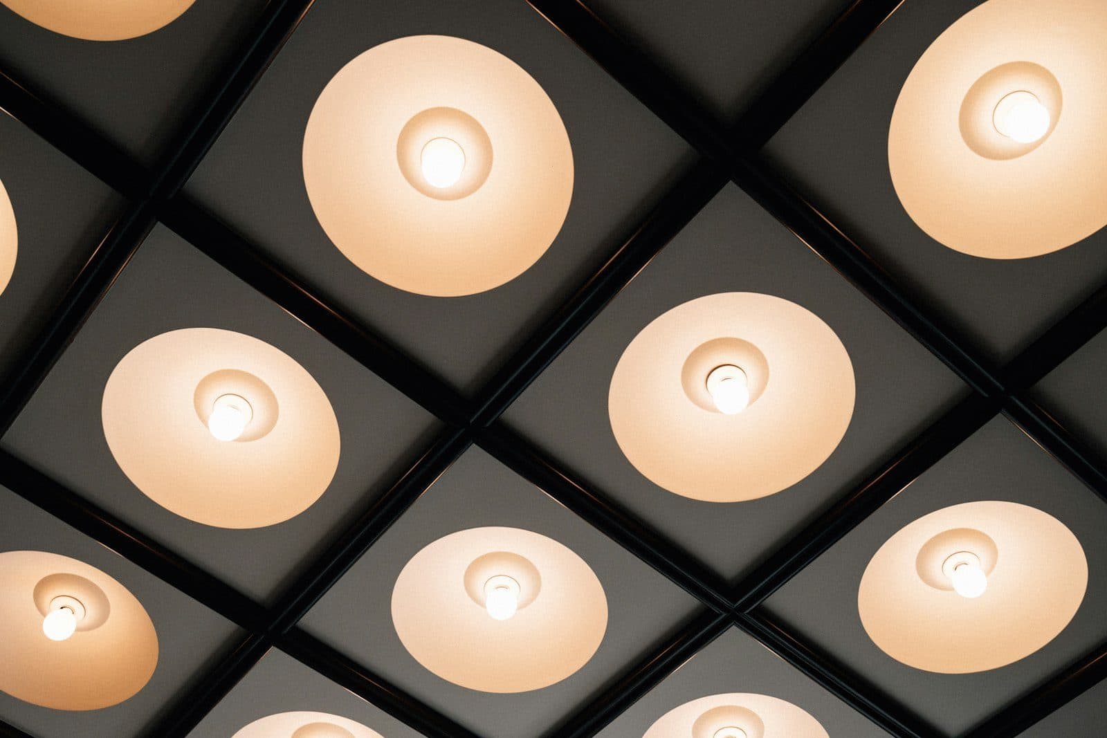 Dark coffered ceiling grid with warm recessed light fixtures set into each panel