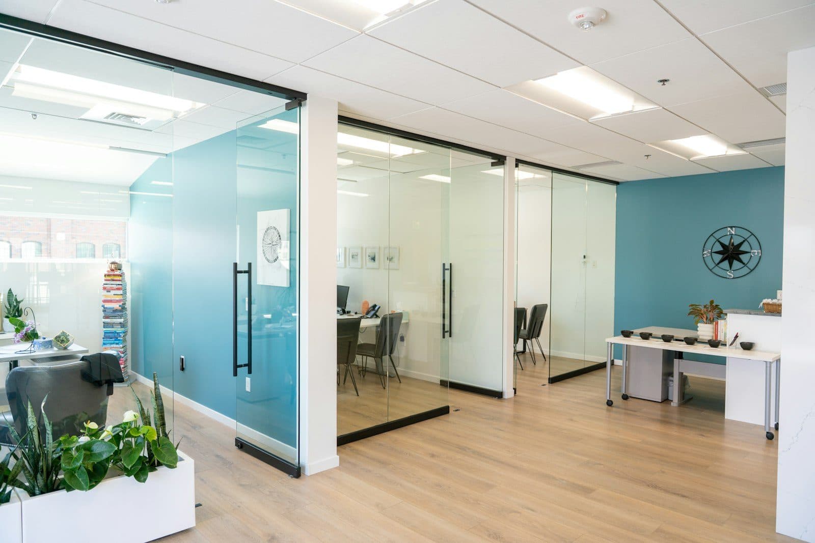 Glass partition walls with sliding glass doors separating meeting rooms from an open-plan office