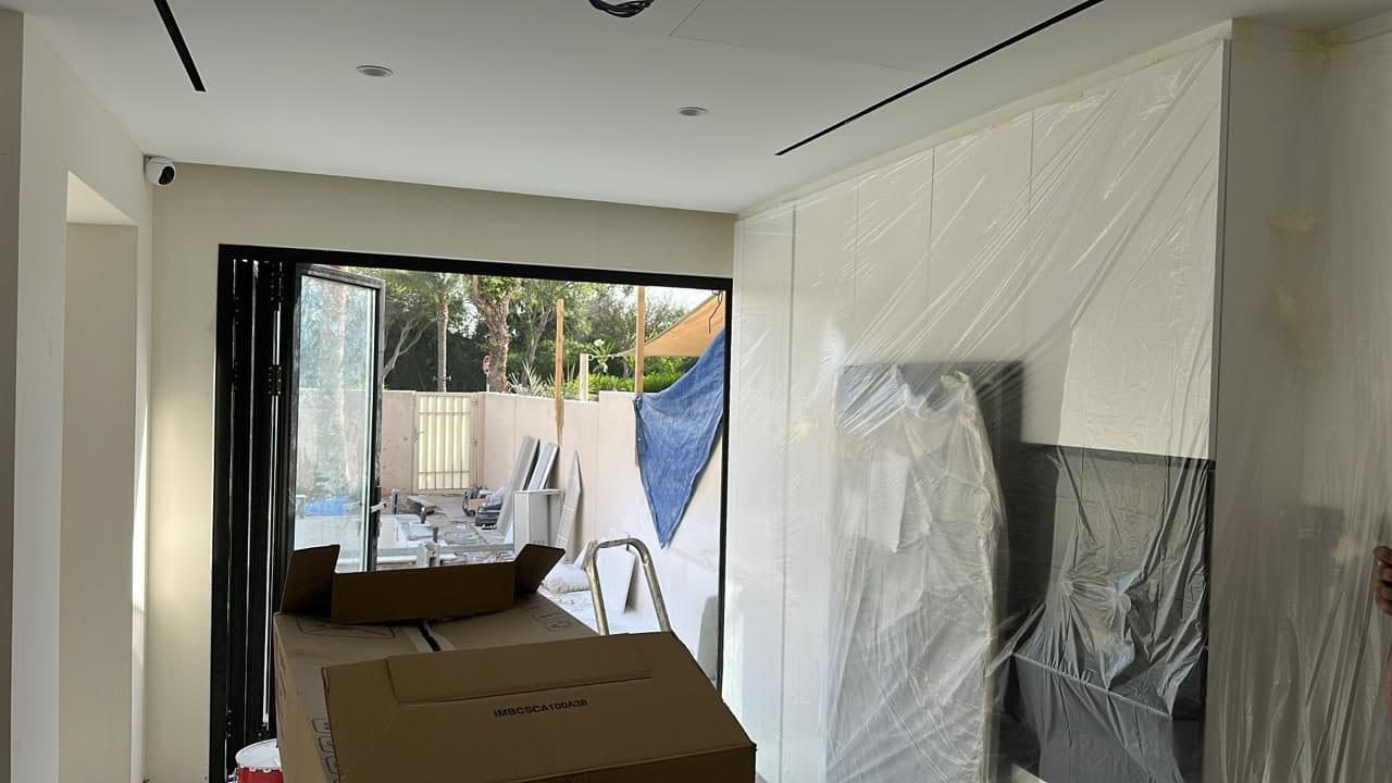 Custom wardrobe and cabinetry panels wrapped in protective film ahead of fitting, staged in a room overlooking the garden.
