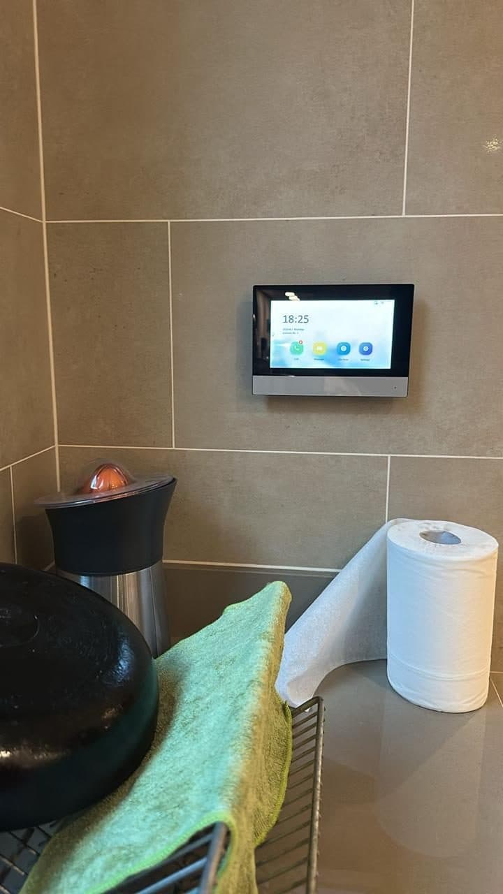 Wall-mounted video intercom panel fitted into a tiled wall corner as part of a villa's smart-entry system.