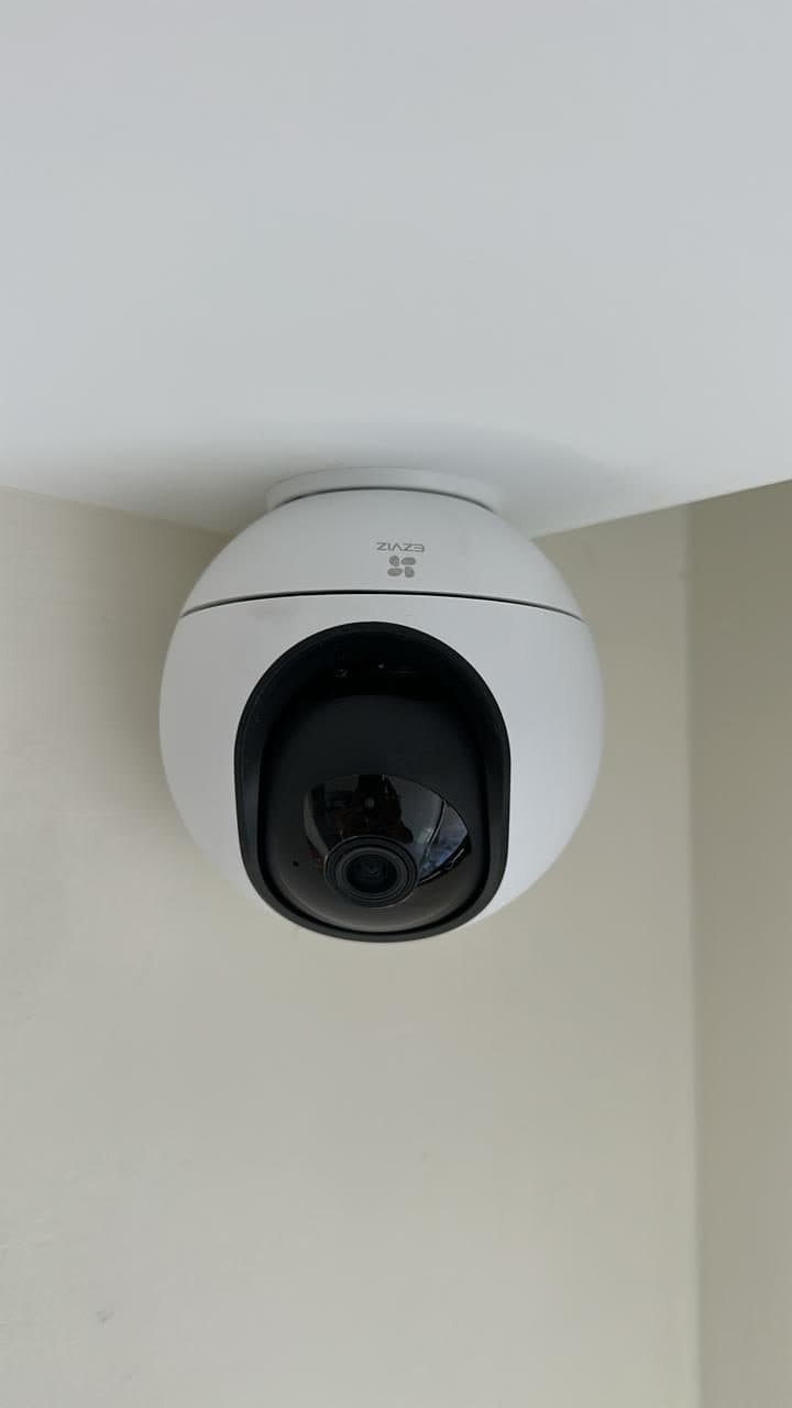 Pan-tilt-zoom dome security camera mounted in a ceiling corner, positioned for full room coverage.