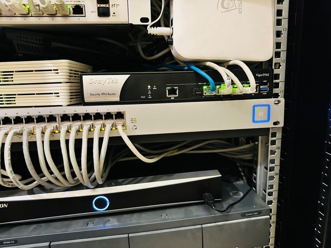 Network rack close-up showing a security VPN router and ONT modem installed alongside a terminated patch panel.