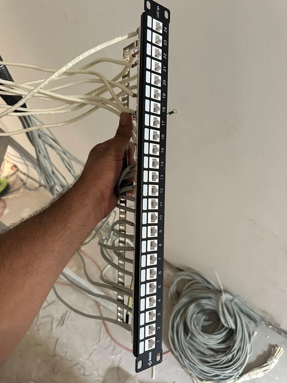 A technician terminating cables onto a 24-port CAT.6A patch panel during a structured cabling installation.