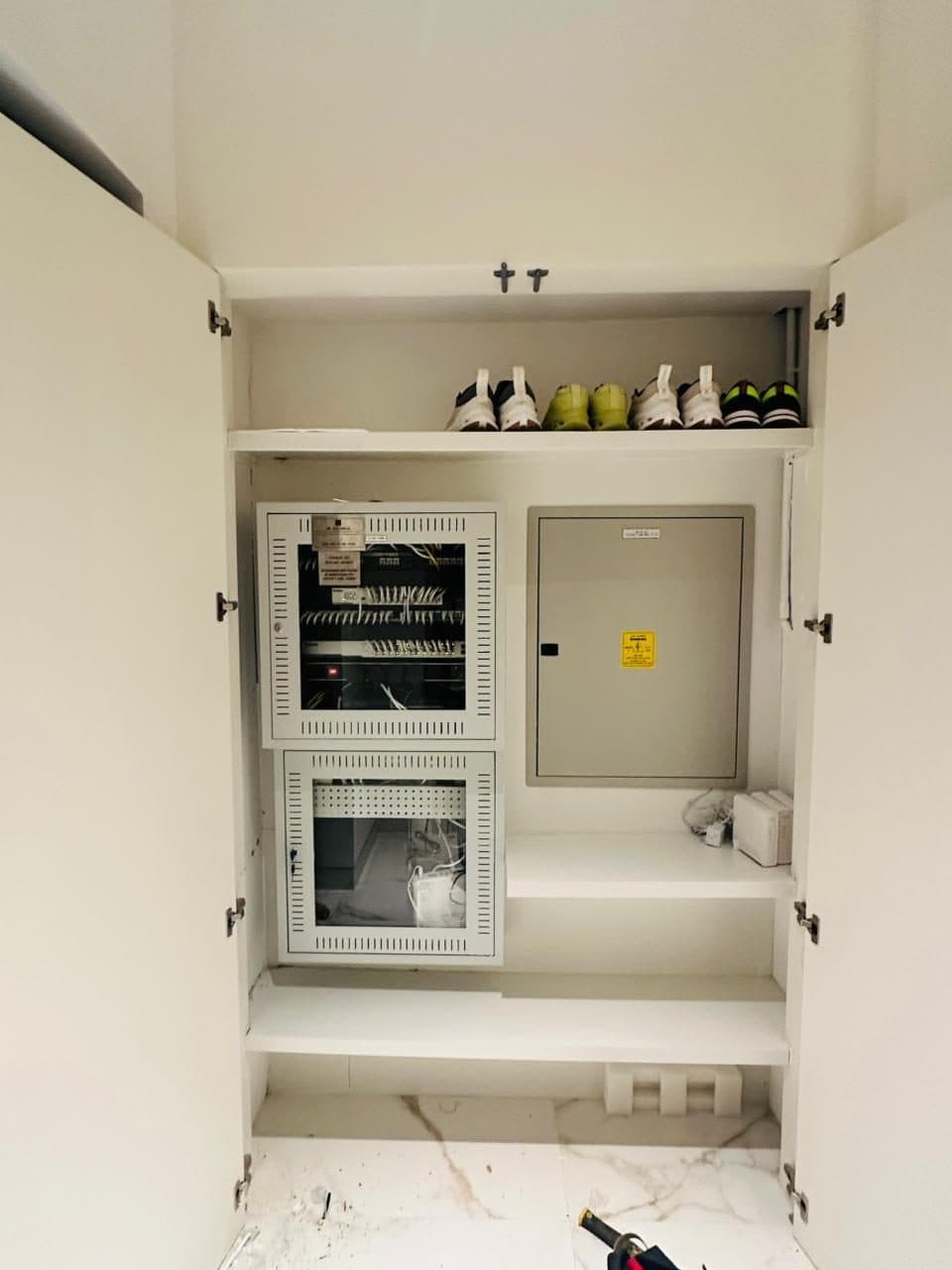 Built-in utility cabinet combining a network patch panel rack with the electrical distribution panel in one dedicated space.