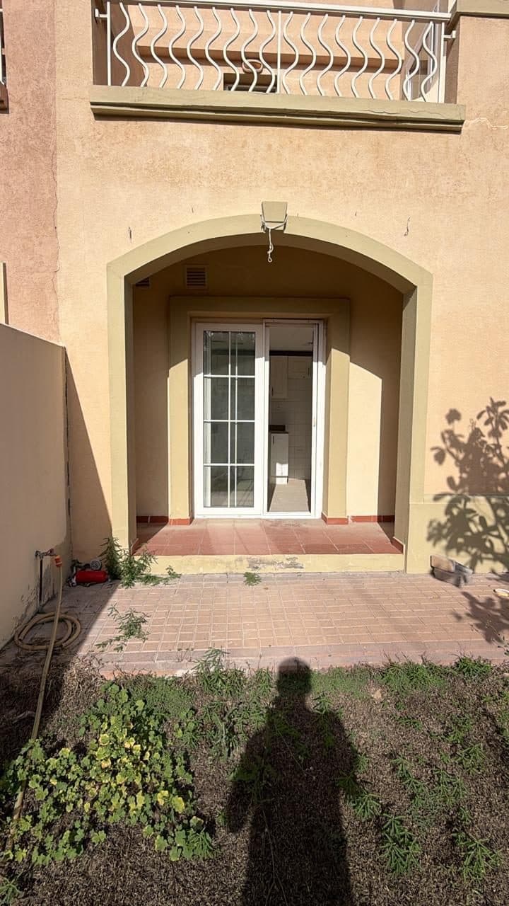 Villa exterior facade with an arched patio, glazed balcony railing above and a tiled outdoor patio floor.