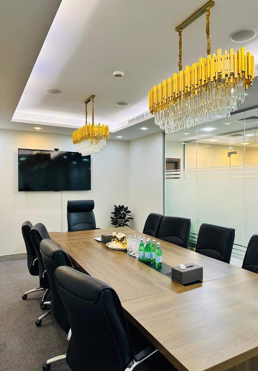 A closer view of the same boardroom's gypsum cove ceiling and recessed lighting, finished around a wall-mounted screen and conference table.