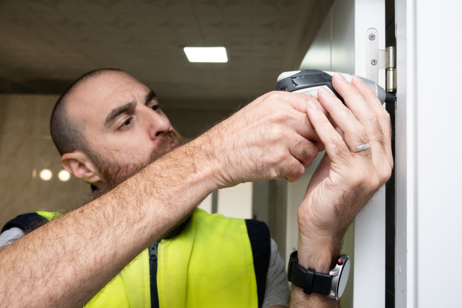 Carpenter fitting a door hinge with a power tool during installation