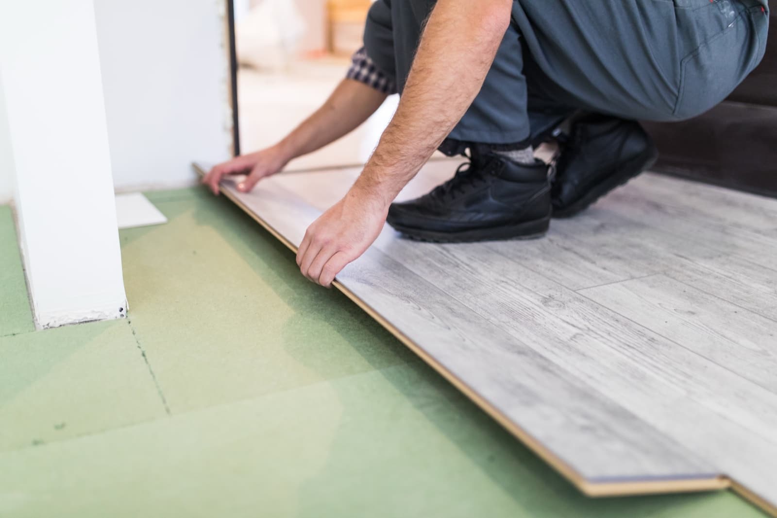 Installer fitting a plank-style floor tile into place beside a doorway