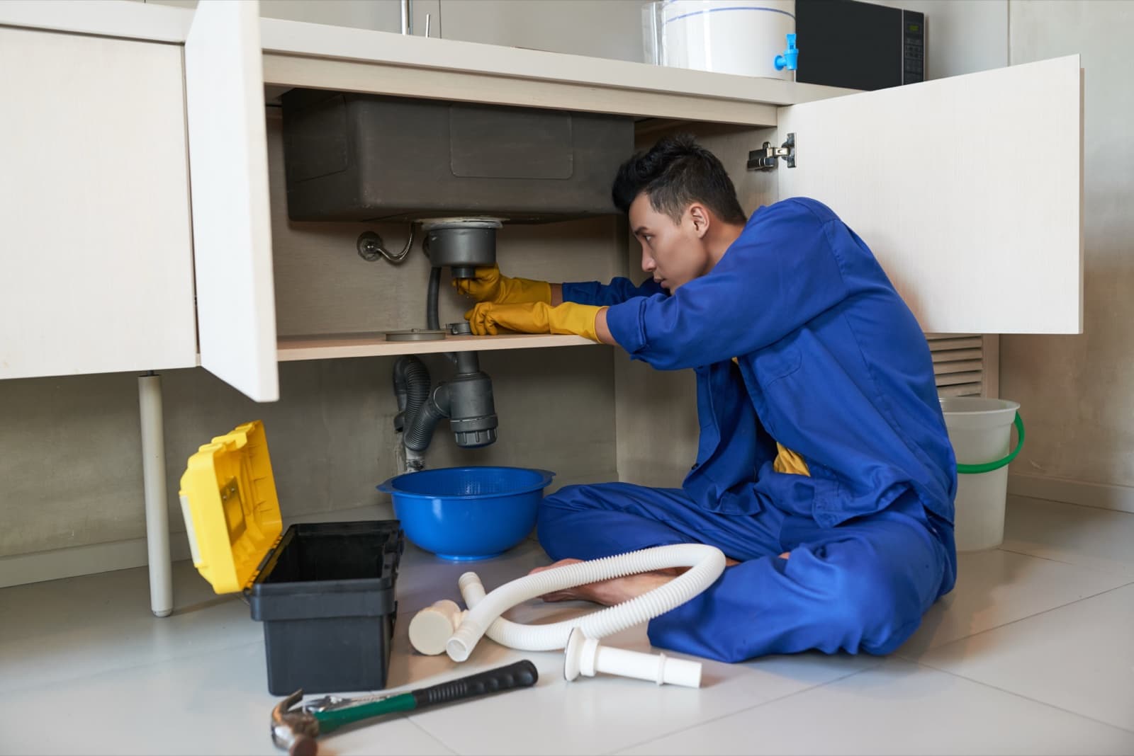 Plumber fitting drainage pipework beneath a bathroom sink