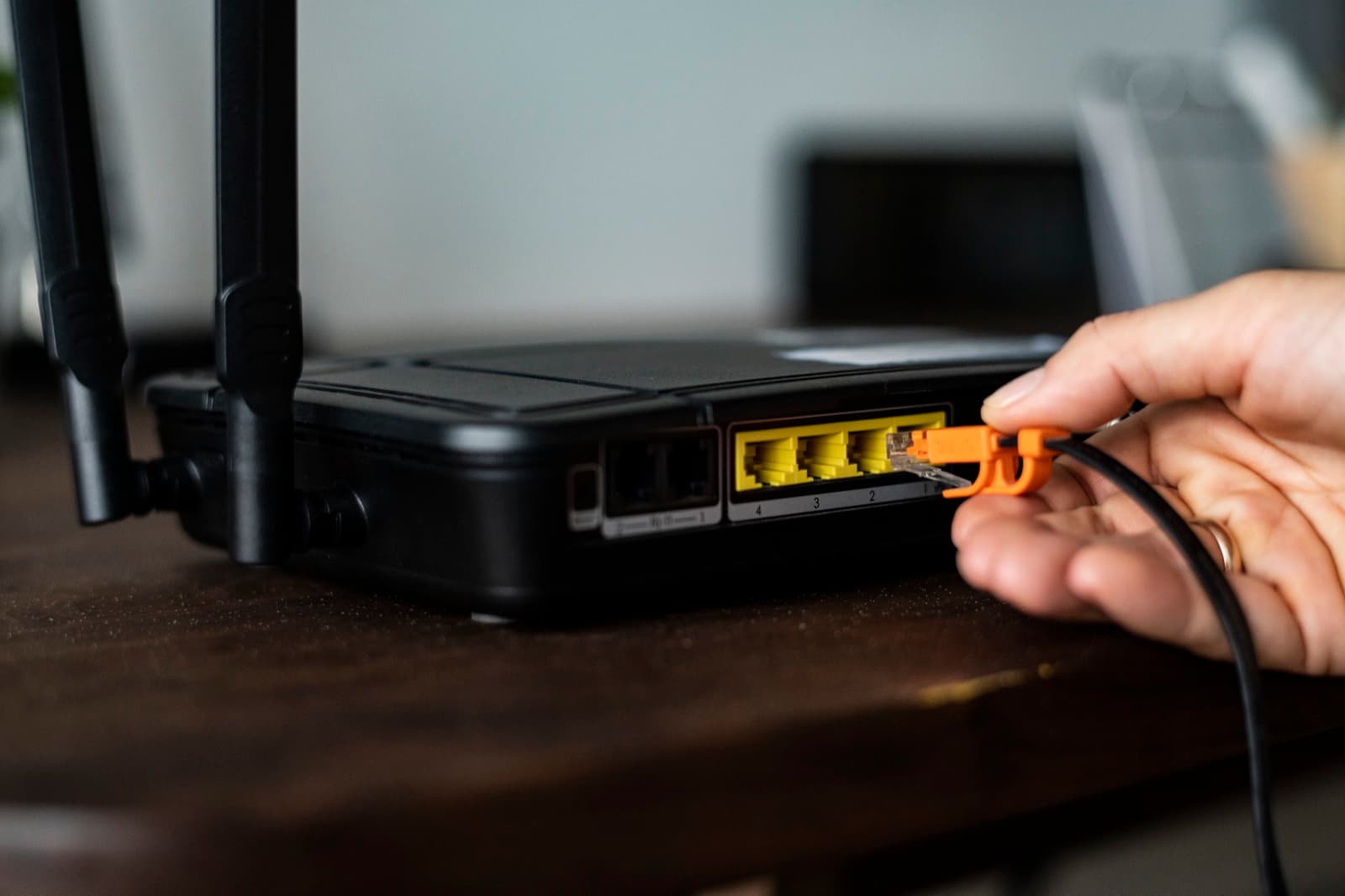 Hand connecting an ethernet cable into a wireless router's port