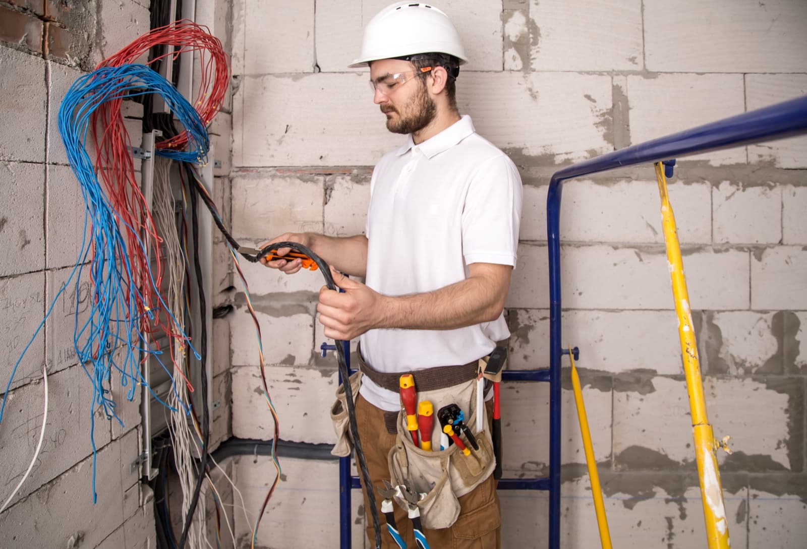 Electrician preparing a bundle of coloured wires beside an open distribution board